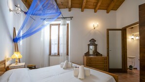 Une chambre d’hôtel avec un lit, une commode en bois, un miroir, une lampe et une fenêtre avec des rideaux.
