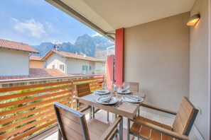 A balcony with a table set for dining, chairs, and a view of mountains. - Casa Margherita in Riva del Garda (Riva del Garda)