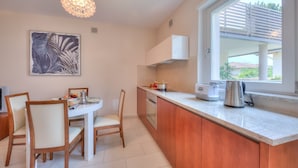 A modern kitchen with a dining area, featuring a large window, a pendant light, and a kitchen island. - Casa Margherita in Riva del Garda (Riva del Garda)