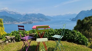 Een prachtig uitzicht op een meer, met bergen op de achtergrond en kleurrijke stoelen in de voorgrond.