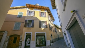 A narrow street with a yellow building featuring a shop with mannequins. - Sergio Il Gufo - Orange in Historic Cente (Toscolano Maderno)
