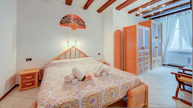 A bedroom with a bed, bedside tables, a wardrobe, and a window with curtains. - Casa Azzurra 150m From Lake (Riva del Garda)