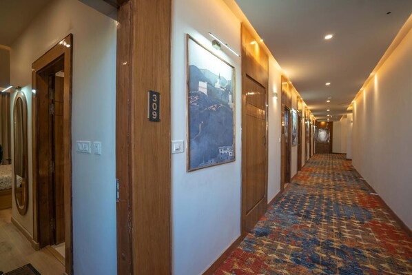 A hotel hallway with wooden doors, a patterned carpet, and a framed picture on the wall. - Hotel Zimskhang Villa (Leh)
