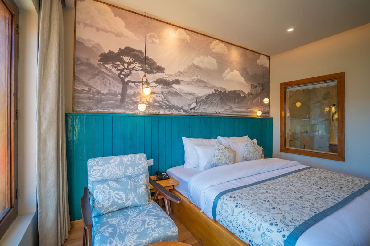 A bedroom with a bed, a chair, a nightstand, and a wall mural.