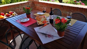 Une table à manger en plein air, avec un mur en briques, des plantes en pot et une vue sur un jardin.