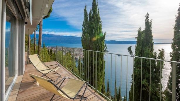 A balcony with a view of a lake and mountains, a chair, and a railing. - Rustichel Lake View in Toscolano Maderno (Toscolano Maderno)