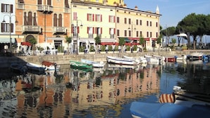 A waterfront with historic buildings, a marina with boats, and a clear sky. - Rustichel Lake View in Toscolano Maderno (Toscolano Maderno)