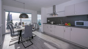 A modern kitchen with white cabinets, a microwave, and a dining area with a table and chairs. - Rustichel Lake View in Toscolano Maderno (Toscolano Maderno)