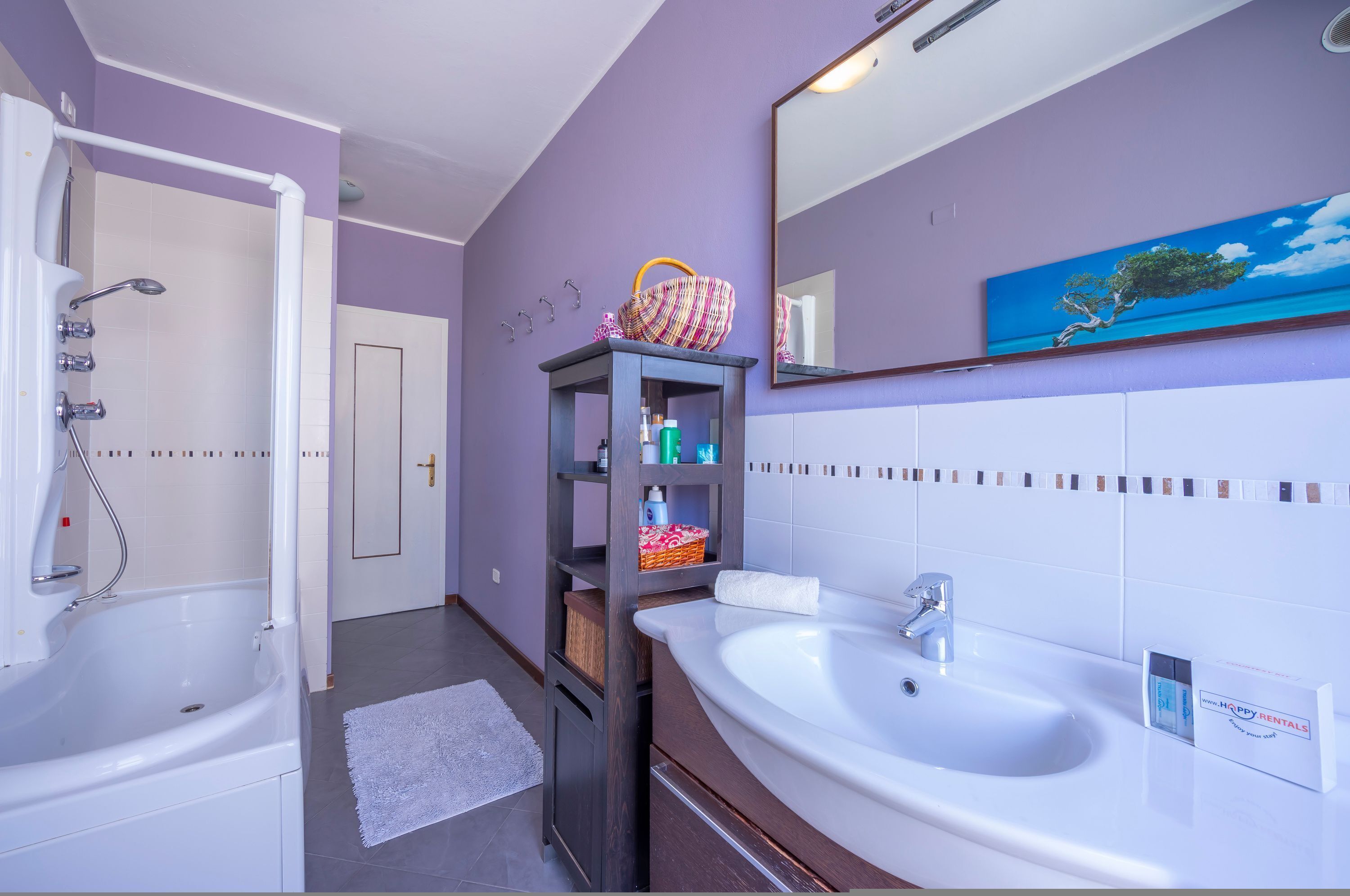 A bathroom with a bathtub, a sink, a mirror, and a shelf with toiletries.