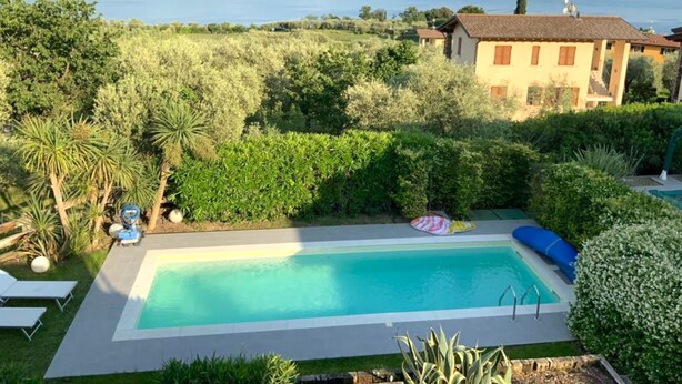 A swimming pool with a view of the sea, surrounded by lush greenery and a villa. - Casa Bougainville With Pool and Lake View (Toscolano Maderno)
