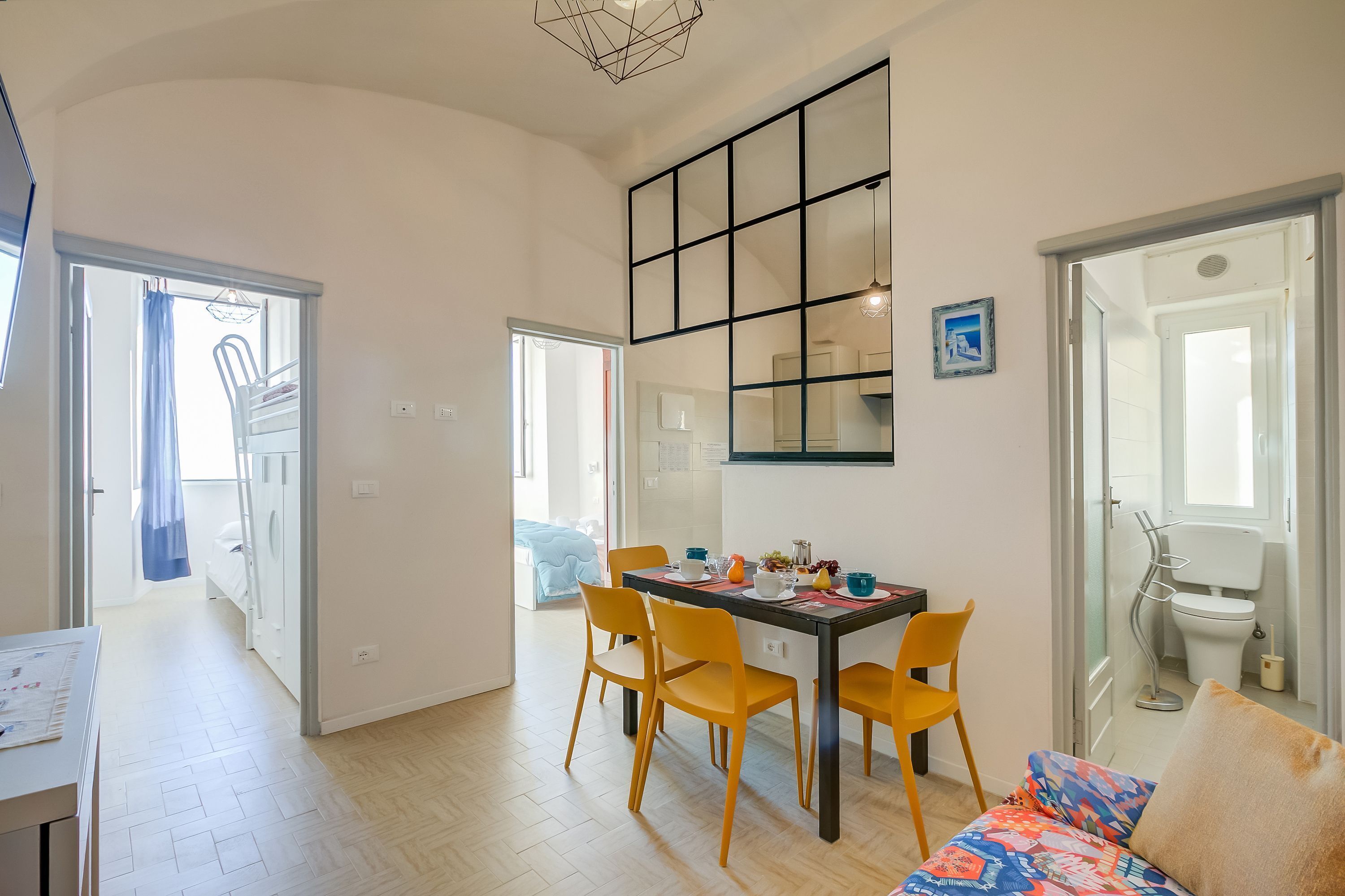 En moderne stue med spiseplads, med et stort vindue, en sofa og et spisebord med stole.