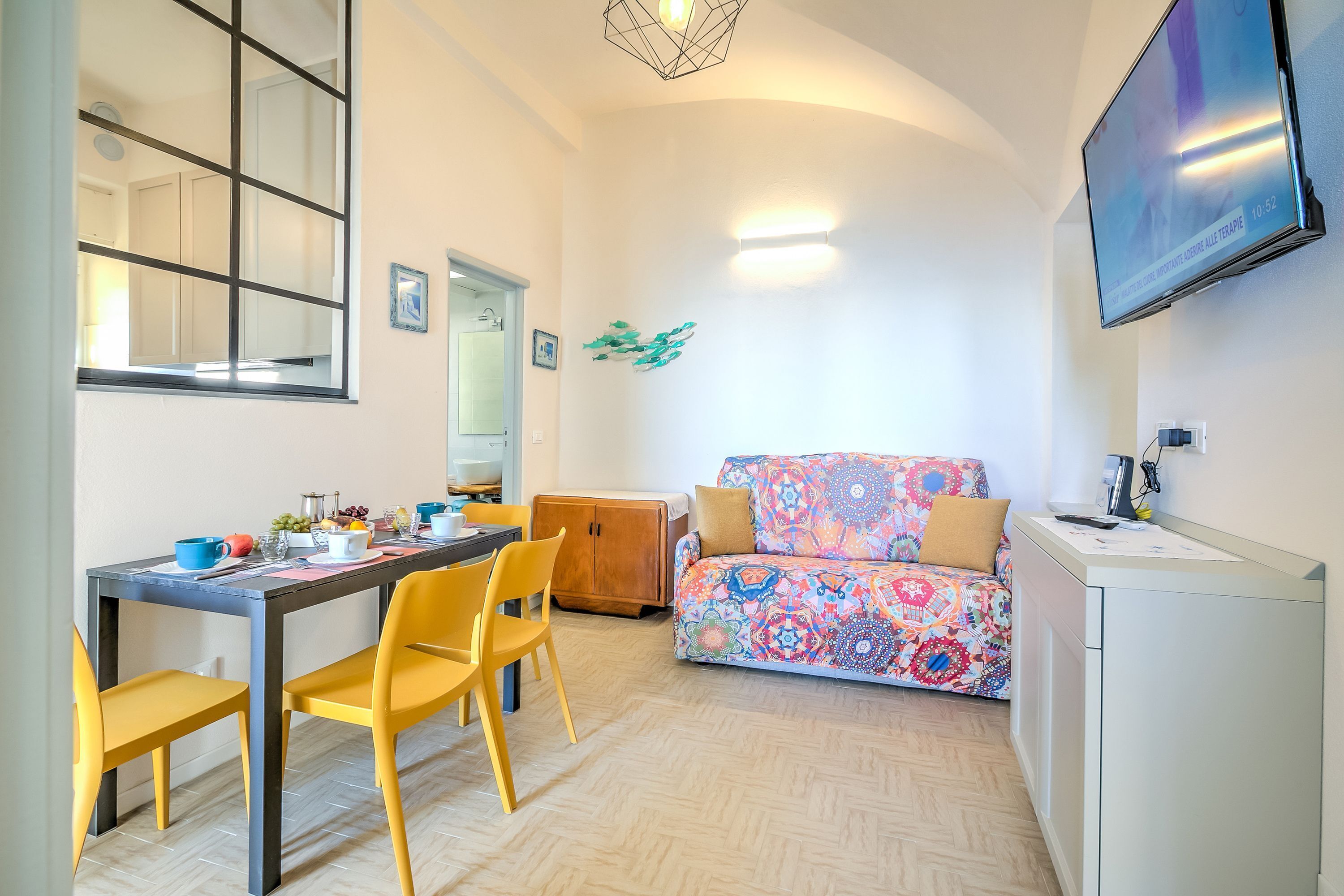 Un soggiorno moderno con un divano, un tavolo da pranzo con sedie e una TV a parete.