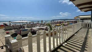 A beachside view with a white fence, beach chairs, umbrellas, and a clear sky. - La Casa Sulla Spiaggia (Alassio)