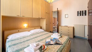 Ein Hotelzimmer mit einem hölzernen Bett, einem Nachttisch mit Lampe, einem Schminktisch und einer Heizung.