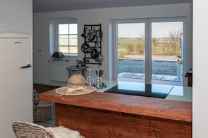 A kitchen with a wooden counter, a refrigerator, a window with a view of the outdoors, and a pot rack. - Holiday Apartment Fiete on the Julshof (Humptrup)