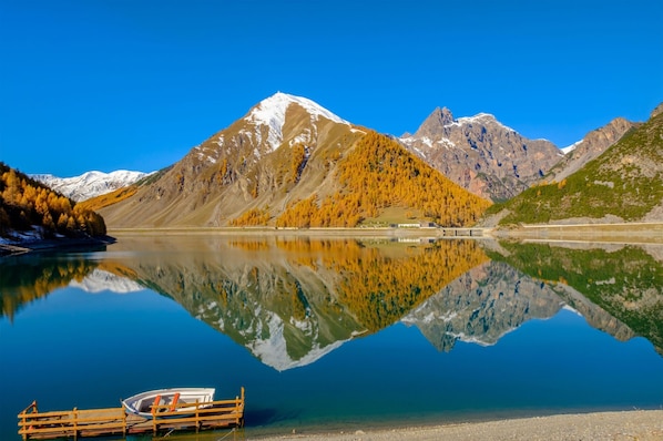 A mountain lake with a boat dock, clear reflections, and a rocky mountain backdrop.