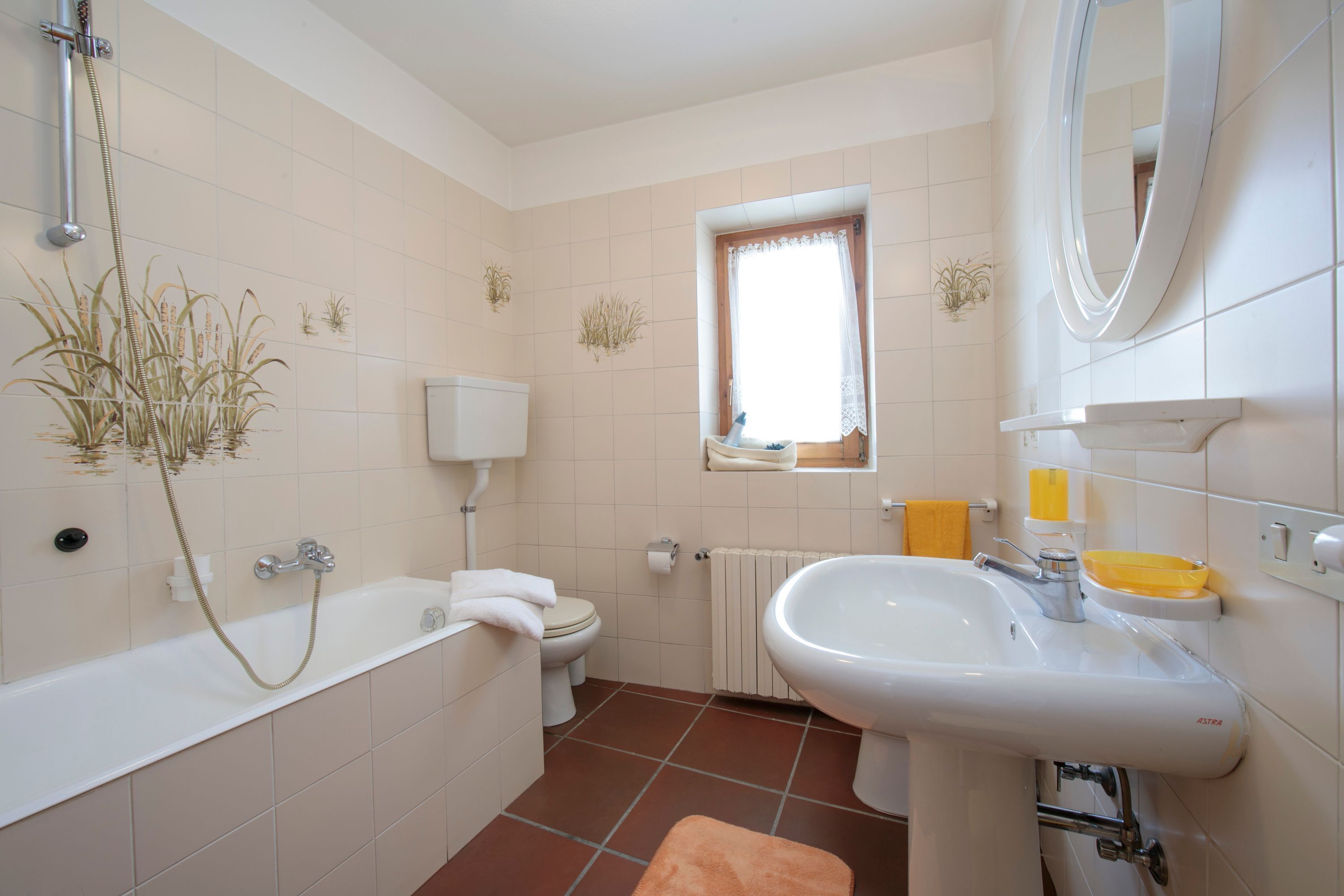 Ein Badezimmer mit Badewanne, Toilette, Waschbecken und Fenster.