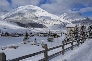 A snow-covered mountain village with wooden buildings and a wooden fence.