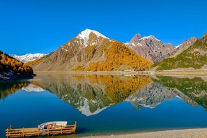 Un lac de montagne avec un quai pour bateaux, des reflets limpides et une chaîne de montagnes rocheuses en arrière-plan.