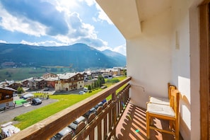 A balcony with a wooden chair, overlooking a town with houses and mountains in the background. - Casa Silvia Ski in in Livigno (Livigno)