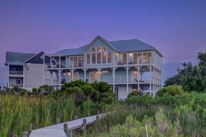 A coastal house with multiple levels, large windows, and a deck. - 4BR - Ocean View / Sound View / North Topsail Beach (North Topsail Beach)