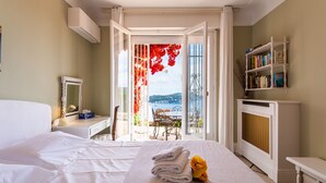 A hotel room with a bed, a bedside table, a mirror, a bookshelf, and a view of the outdoors. - ROMANTIC VILLA VI4412 By Riviera Holiday Homes (Villefranche-sur-Mer)