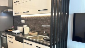 Moderni keittiö, jossa on valkoiset kaapit, musta työtaso ja sisäänrakennettu astianpesukone.