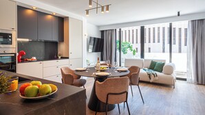 Eine moderne Küche mit Essbereich, einer Couch und einem großen Fenster mit Vorhängen.