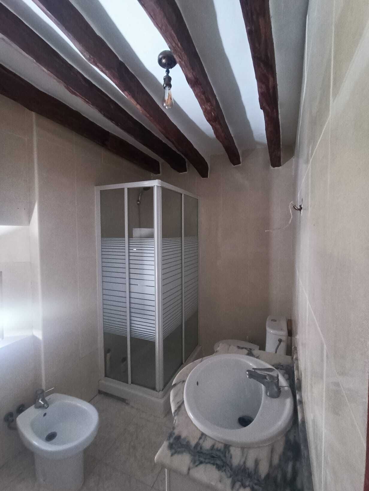 Een badkamer met een douchecabine, een wastafel en een toilet met douchefunctie.
