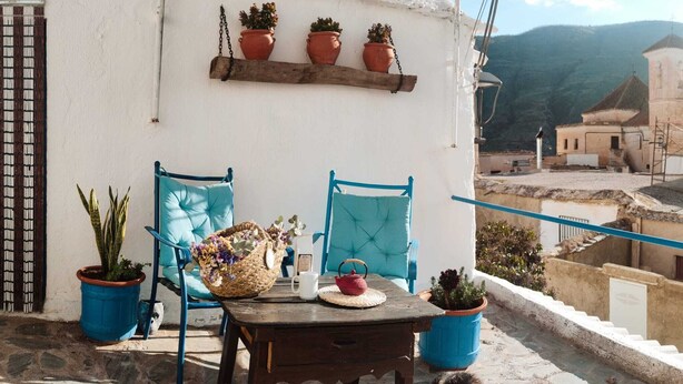 Um terraço com mesa, cadeiras e plantas em vasos.