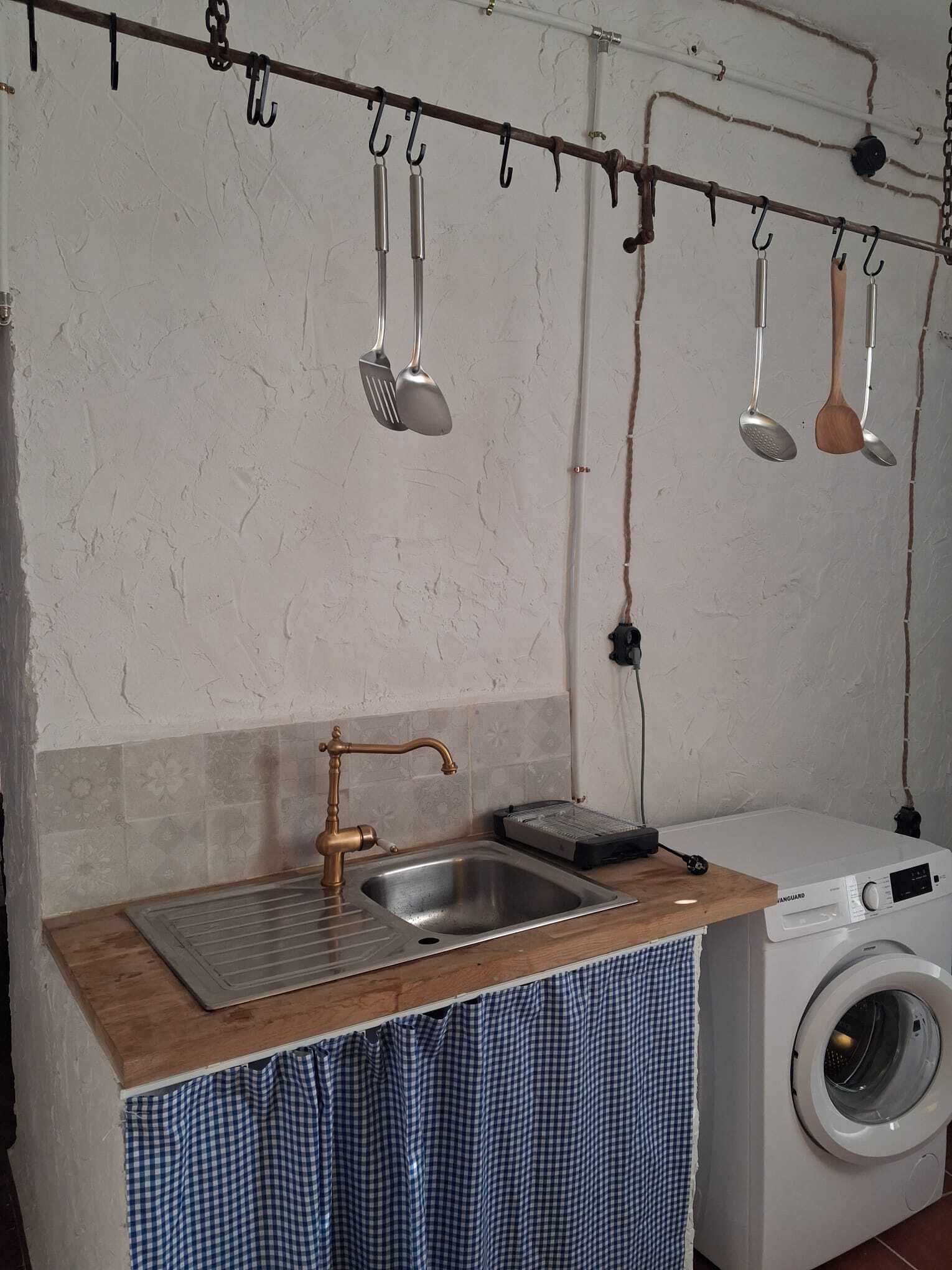 A compact kitchen with a sink, a washing machine, and a drying rack.