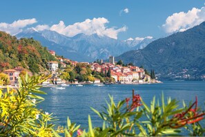 A lakeside town with buildings along the shore, a prominent tower, and mountains in the background. - Appartamento Bella Vista (Sirmione)
