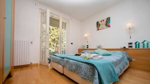 Un dormitorio con cama, ventana, radiador y una lámpara fijada a la pared.
