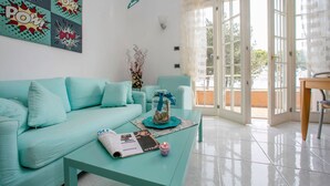 Una sala de estar con un sofá turquesa, una mesa de centro con una revista y una vela, y un frasco de vidrio con un lazo azul.