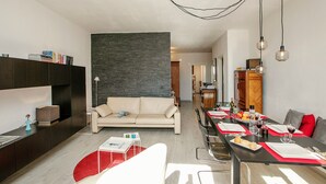 Una sala de estar moderna con un sofá, una mesa de comedor y una zona de cocina al fondo.