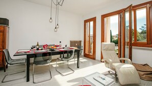 Un comedor con una mesa dispuesta para cuatro, una butaca reclinable y vistas a través de la puerta abierta.