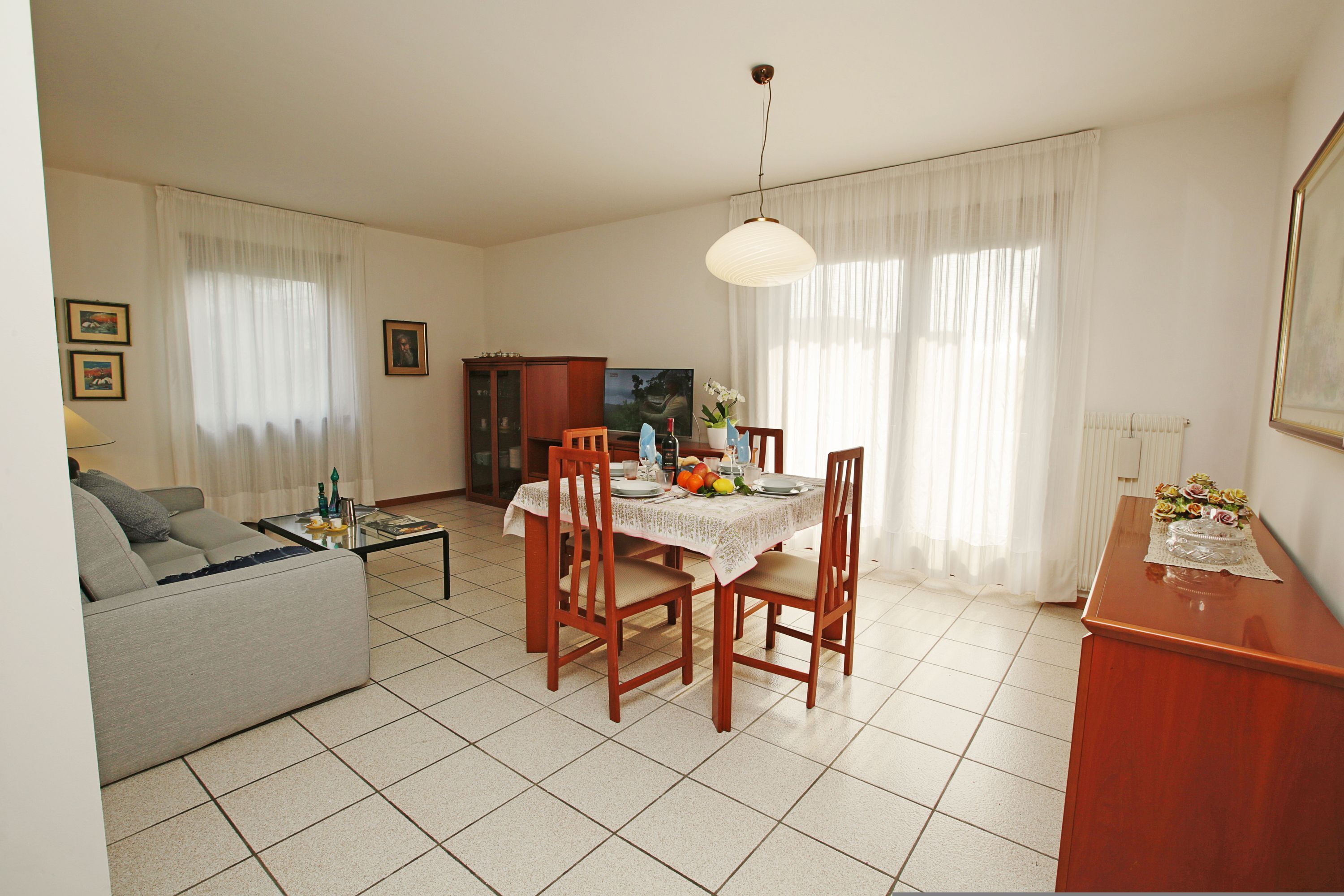 Ein Wohnzimmer mit einer Couch, einem Esstisch mit Stühlen, einem Couchtisch und einem Fernseher.