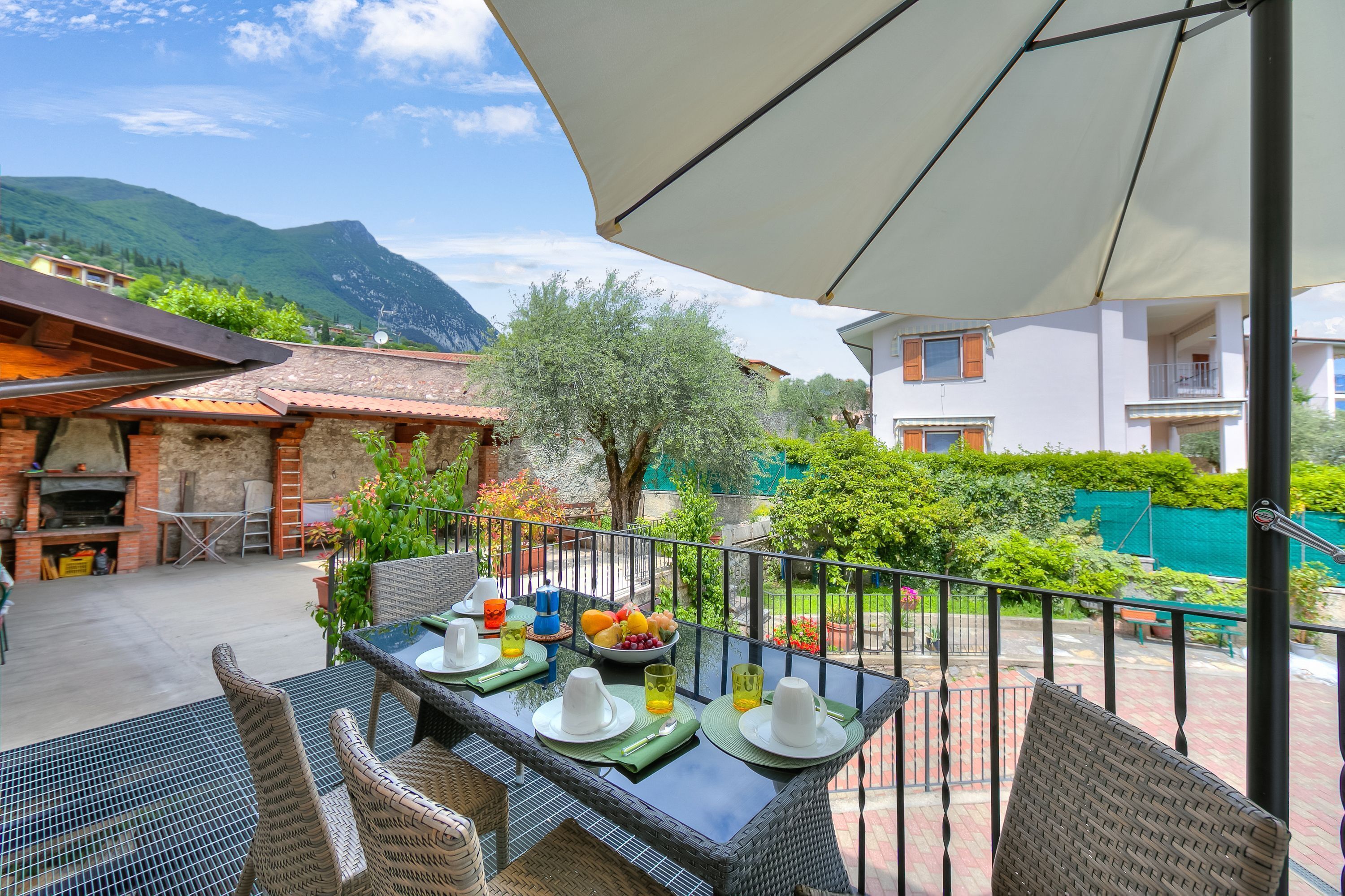 An outdoor dining area with wicker chairs and a table set for two, overlooking a mountainous landscape.