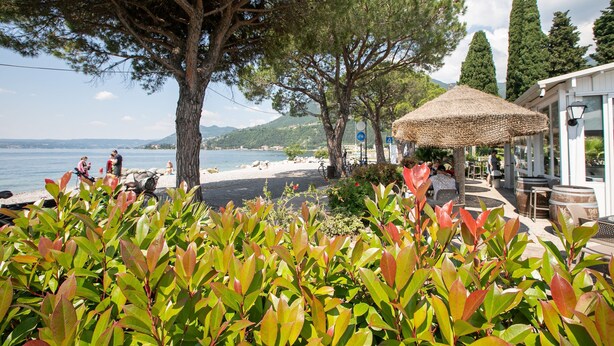 A coastal area with a beach, outdoor seating, and a view of the sea.