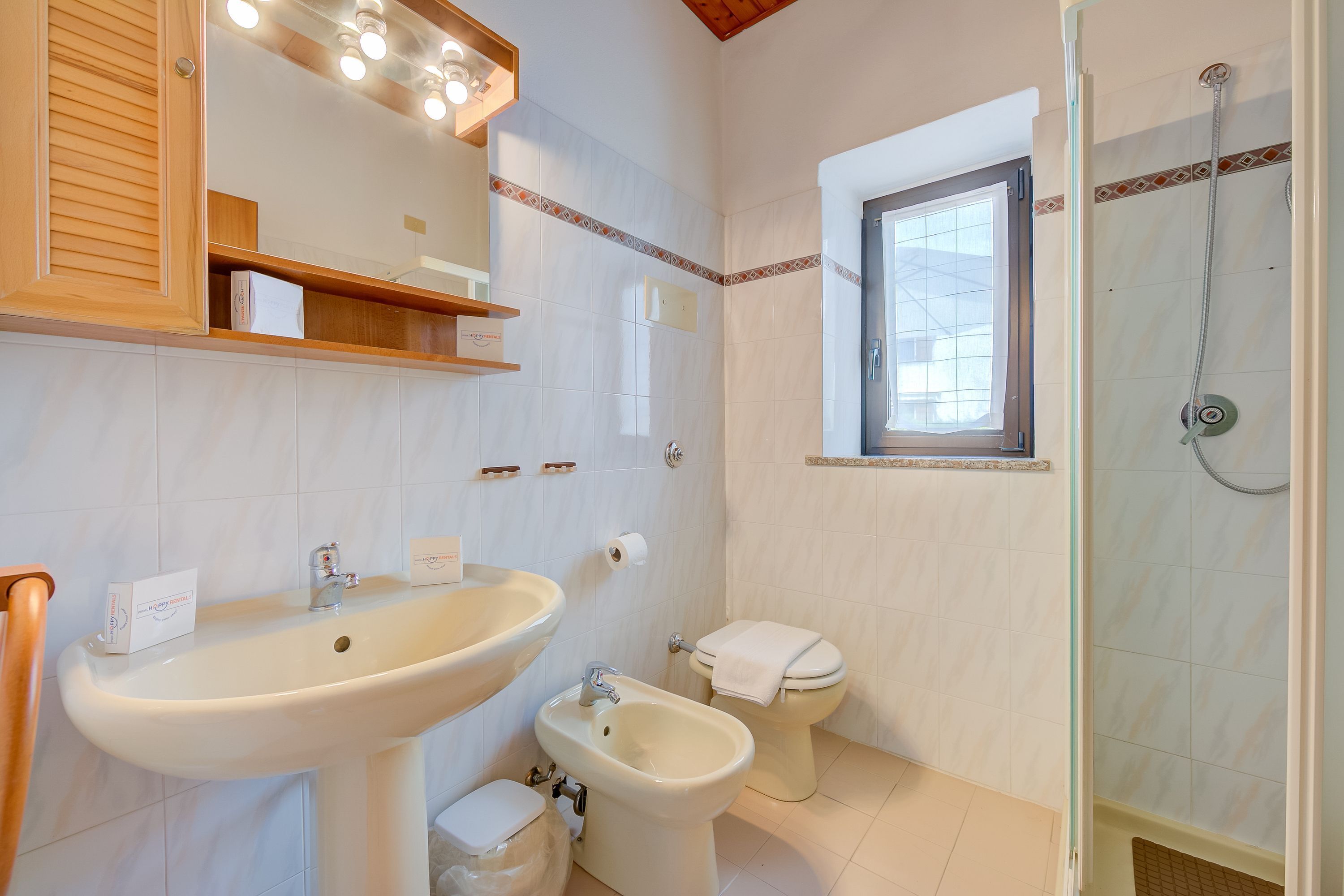 A bathroom with a sink, bidet, toilet, and shower.