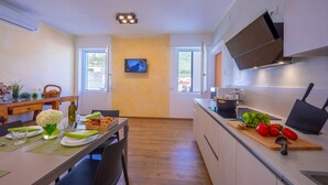 Eine moderne Küche mit einem Holztisch, einem an der Wand montierten Fernseher und einer Kücheninsel mit frischem Gemüse.