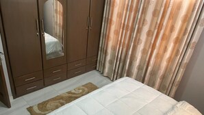 Een slaapkamer met een bed, een kledingkast en gordijnen.
