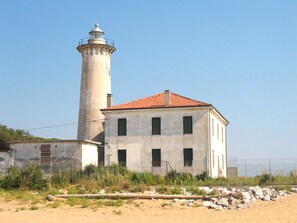 Un phare avec un toit recouvert de tuiles rouges et un bâtiment blanc doté de nombreuses fenêtres.