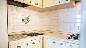 A kitchen with white cabinets, a stainless steel sink, and a gas stove. - Spacious apartment with sea view - Beahost (Bibione)