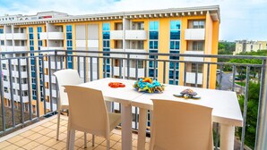 A balcony with a white table and chairs, a small sculpture, and a bag of snacks. - Spacious apartment with sea view - Beahost (Bibione)