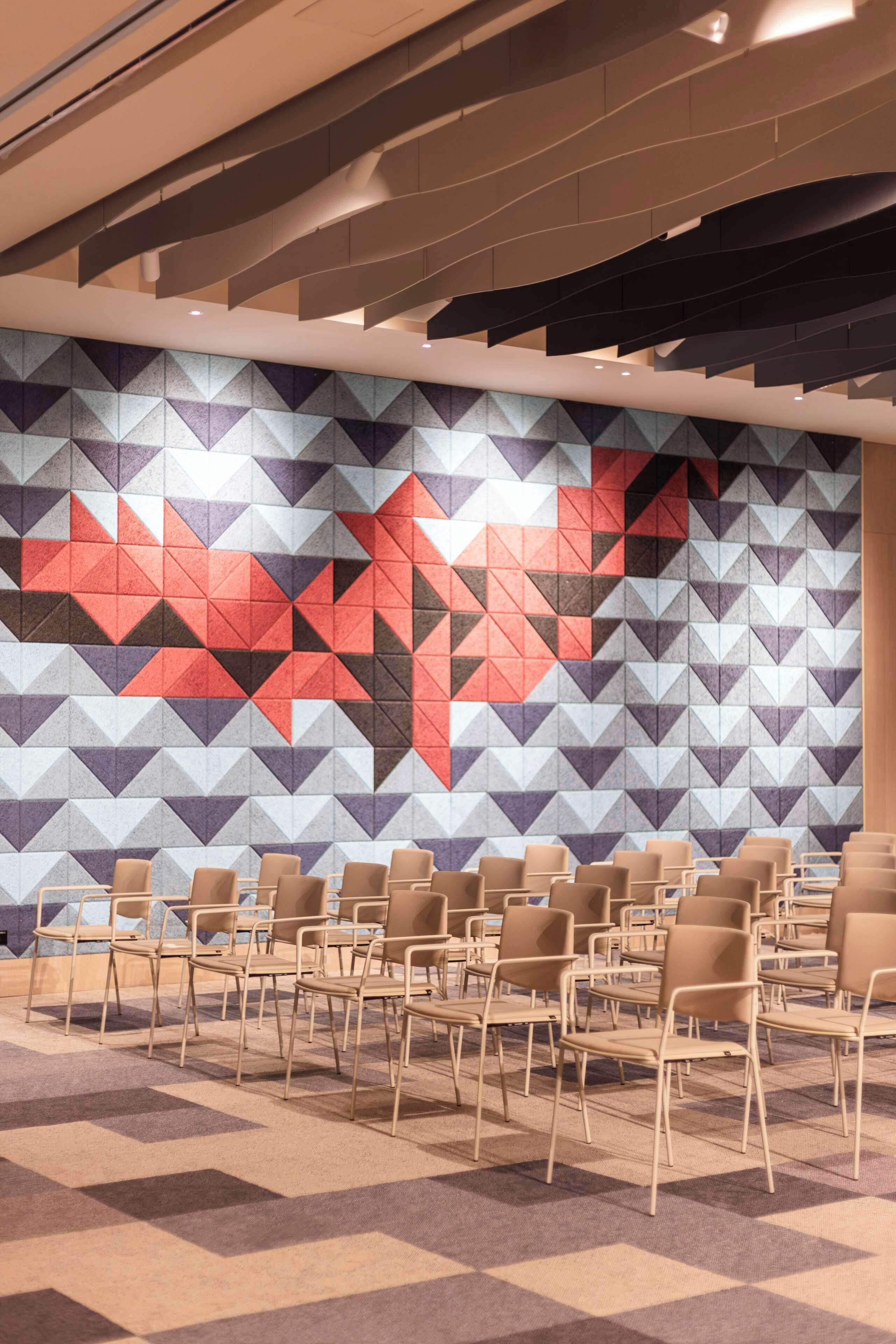 A conference room with a geometric patterned wall and rows of chairs.
