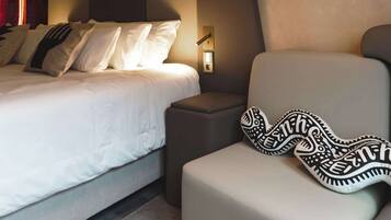 A modern bedroom with a bed, a sofa, a hanging light fixture, and a wall-mounted lamp.