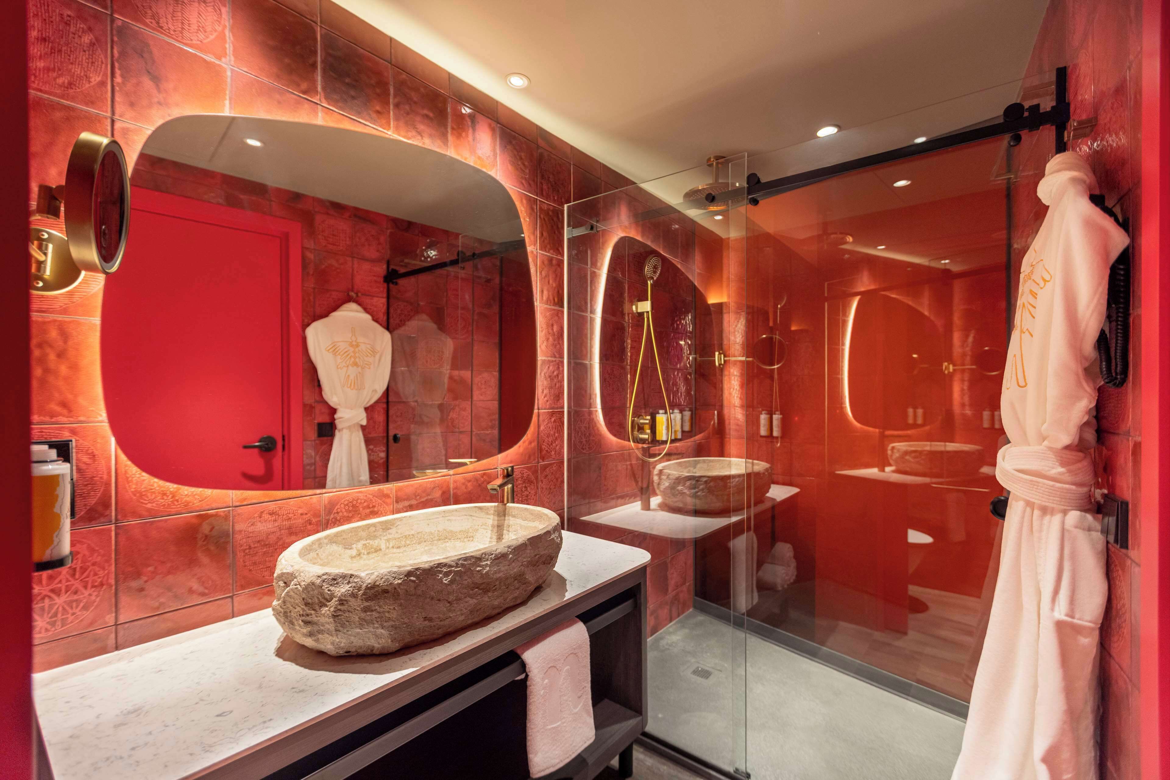 A modern bathroom with a stone sink, large mirrors, and a glass shower enclosure.