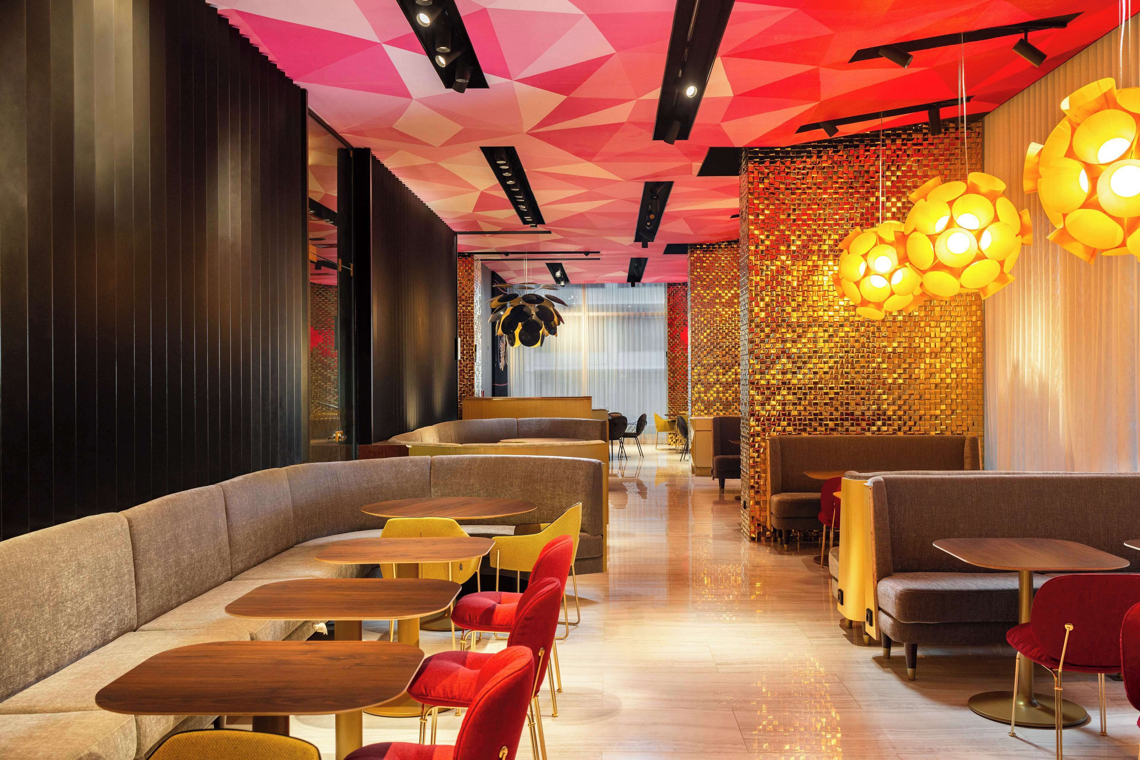 A modern restaurant interior with seating arrangements, including booths and tables, and a decorative ceiling.