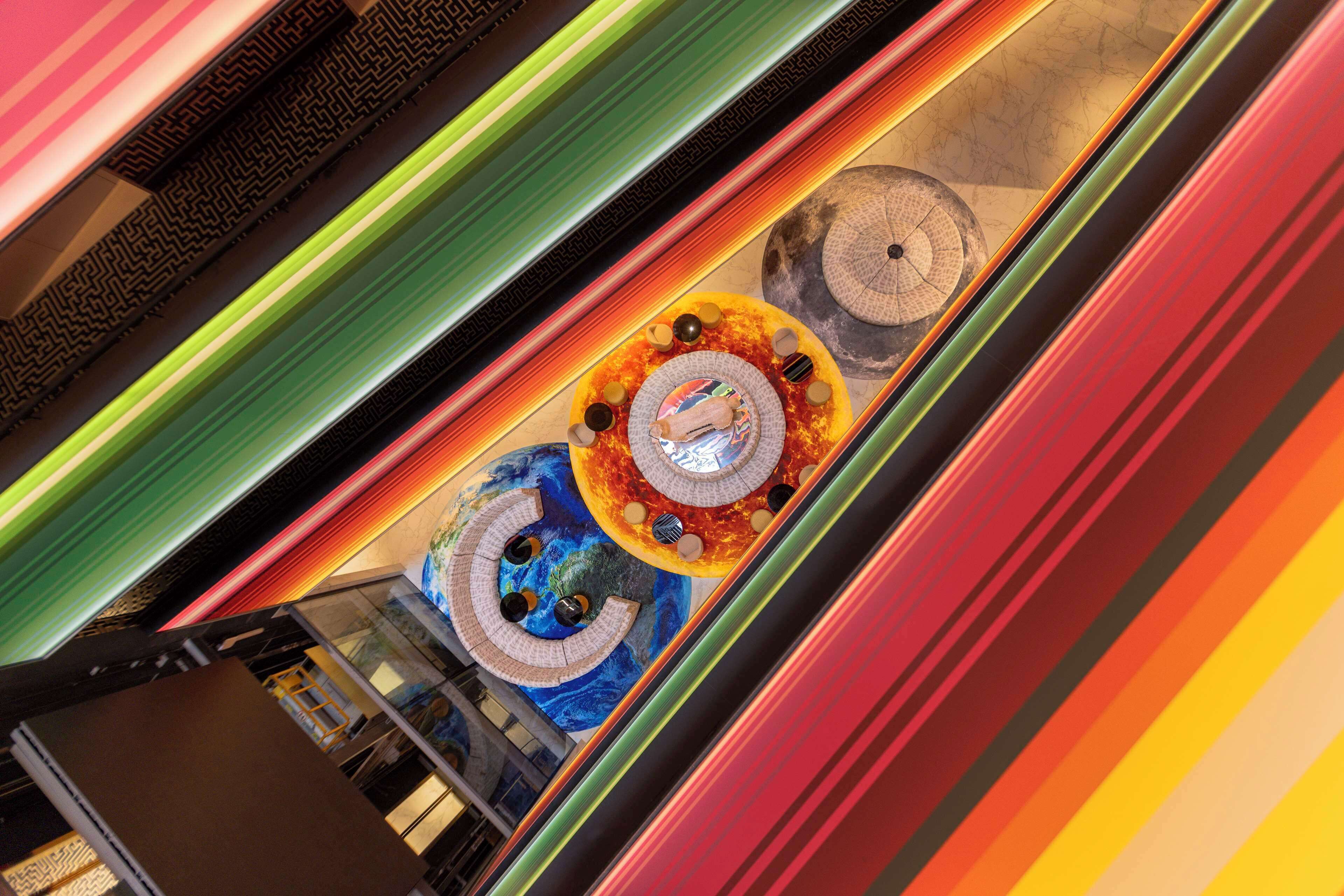 An escalator with a colorful, artistic design featuring circular patterns and a central decorative element.